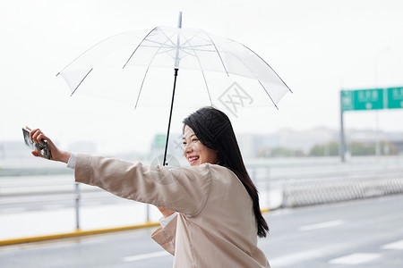 户外撑伞拦车的年轻女性高清图片