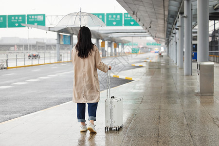 在室外在机场室外撑伞等车的女性背影背景