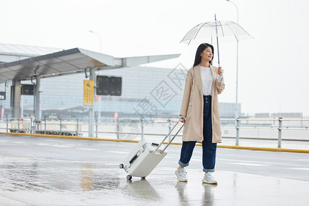 下雨天撑伞拖行李的女性背景图片