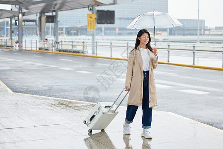 下雨天撑伞拉着行李的女性图片