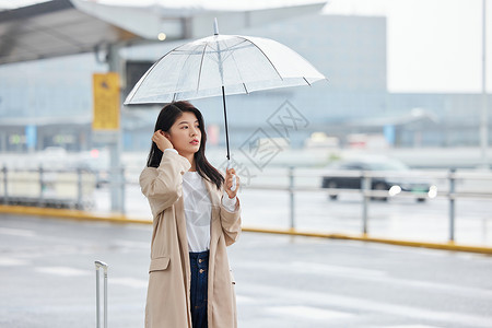 下雨撑伞等车的女性背景图片
