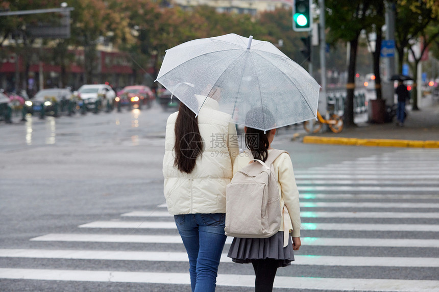 下雨天母女撑伞牵手过人行道背影图片