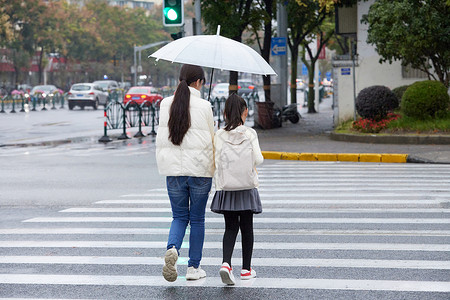 小孩过马路下雨天母女撑伞牵手过人行道背景