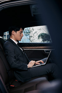 年轻商务白领坐在轿车里用笔记本电脑办公高清图片