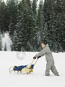 在雪里推着车行走的男人图片