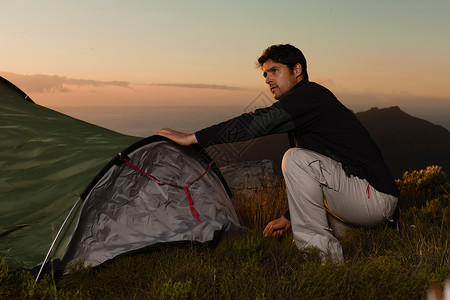 男人在山坡上架设帐篷背景图片