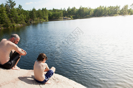 父亲和儿子坐在湖边图片