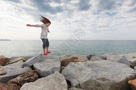 女孩在海岸礁石上蹦跳图片