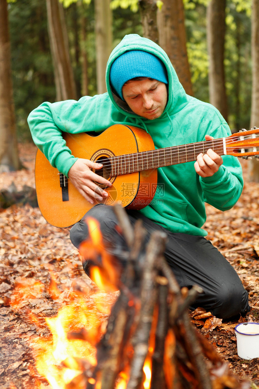 在营火旁弹吉他的人图片