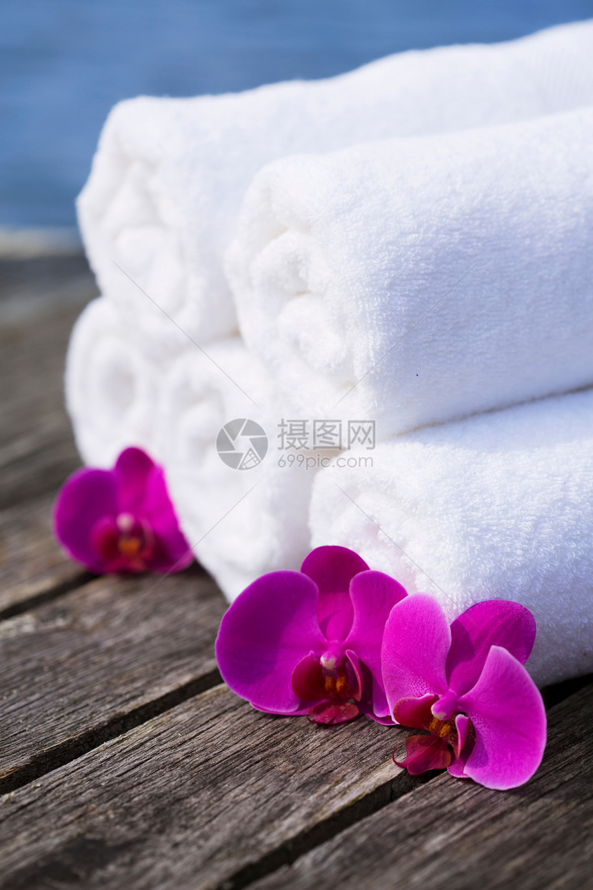 木板桌上的蓝色毛巾和紫色花朵图片