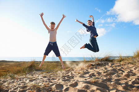男孩和少女在海滩上跳跃图片