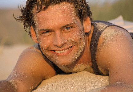 男人在海滩上趴在沙子上背景图片