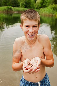 在湖边手握着小爬行动物的少年男孩图片