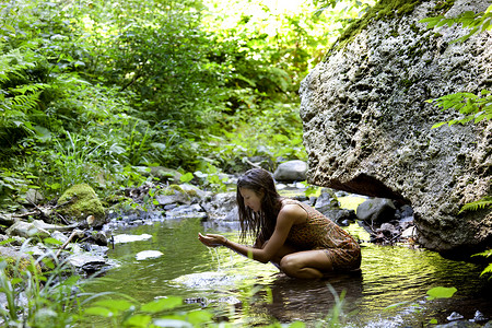 少女半蹲在溪水中图片