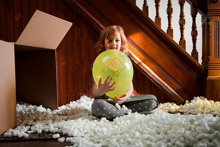 女孩玩气球和纸箱包装材料背景图片