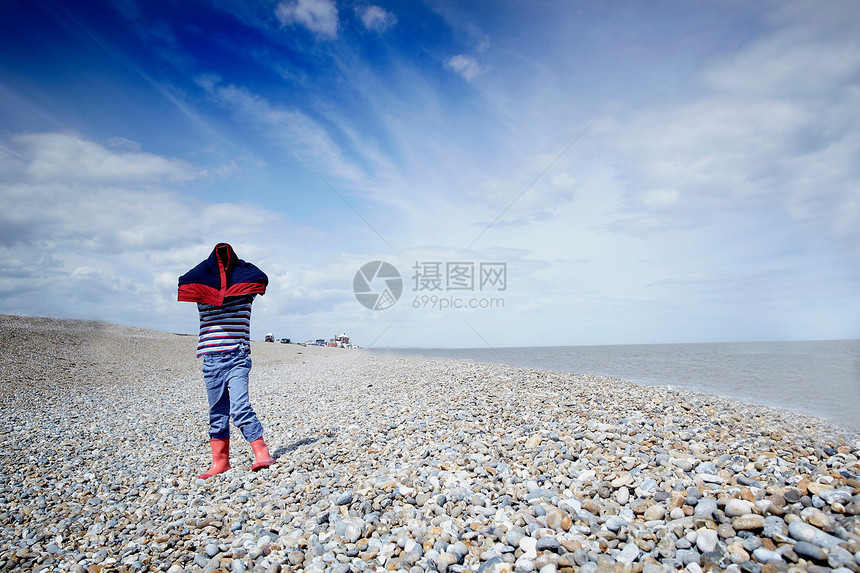在石头沙滩上盖着大衣的男孩图片