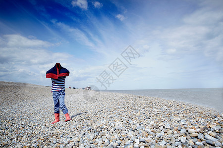 一宅定江山在石头沙滩上盖着大衣的男孩背景