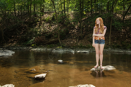 少女站在河边的岩石上图片