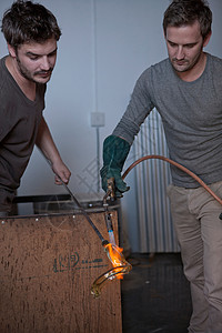 工厂中的两个男子夹着加热球制作高清图片素材