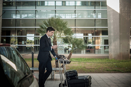 青年男子在机场使用行李推车图片
