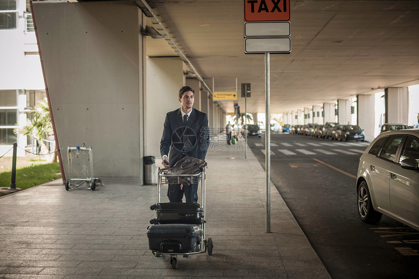 在机场推行李推车的年轻人图片
