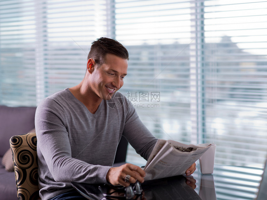 成人中年男子坐在桌子上看报纸图片