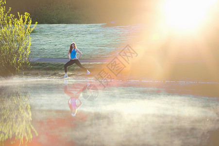 少女在阳光迷雾下的湖边漫步图片