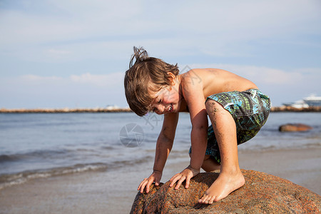 男孩在海滩的岩石上玩耍微笑高清图片素材