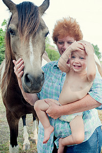 祖母抱着小孩跟马玩耍图片