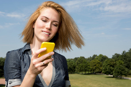 在公园看手机的年轻女人图片