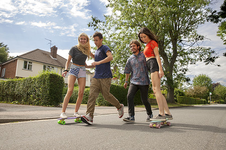 女子玩滑板两对年轻夫妇在路上玩滑板背景