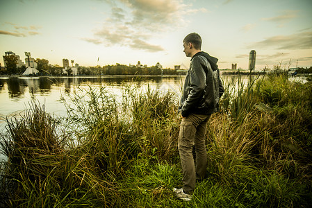 站在草地上看着水的俄罗斯年轻人图片