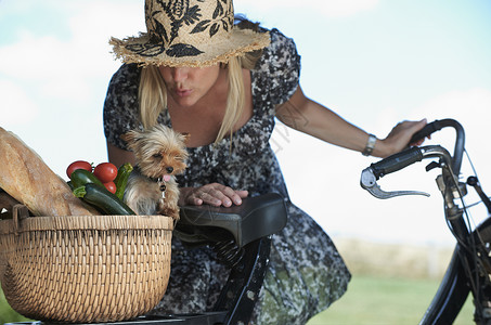 骑电动车带着小狗和一筐蔬菜的女人图片