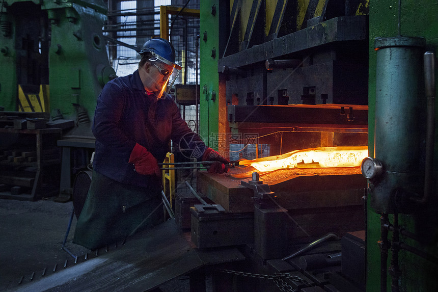 工厂工人用钳子钳起锻造的金属图片
