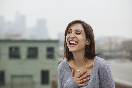 在城市屋顶上大笑的女人享乐高清图片素材