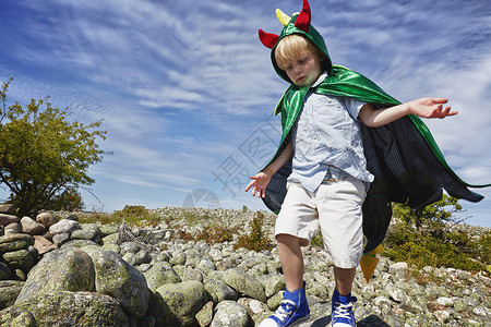 男孩身穿绿色斗篷在石子上行走图片