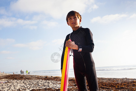海滩上拿着冲浪板的男孩夏天高清图片素材