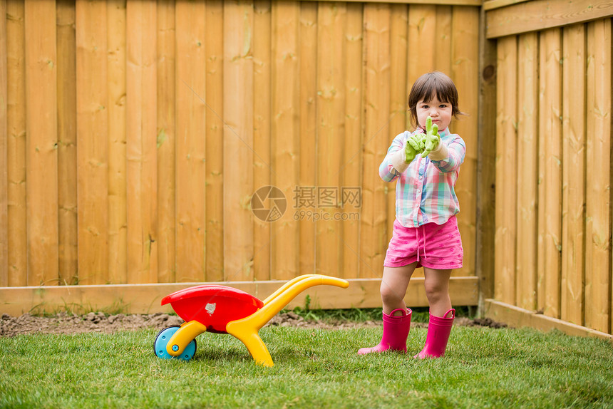 带着玩具手推车的小女孩戴上园艺手套图片