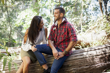 坐在森林树干上的年轻夫妇笑高清图片素材