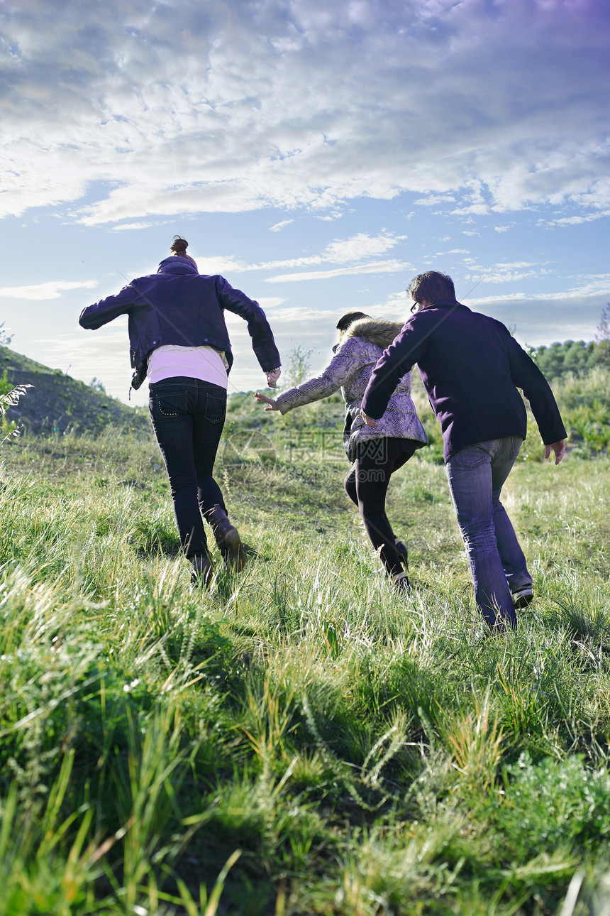 三个年轻的朋友在草地上奔跑图片