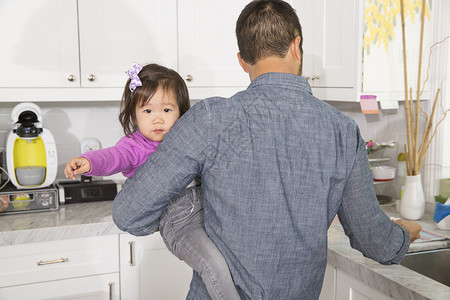 在厨房中怀着女儿的成人男子可爱的高清图片素材