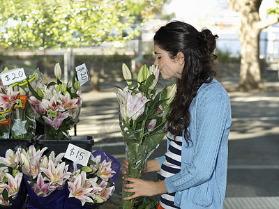 在街头花店闻着花香味的年轻女子图片