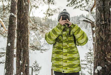 在雪覆盖的森林拍摄照片的人图片