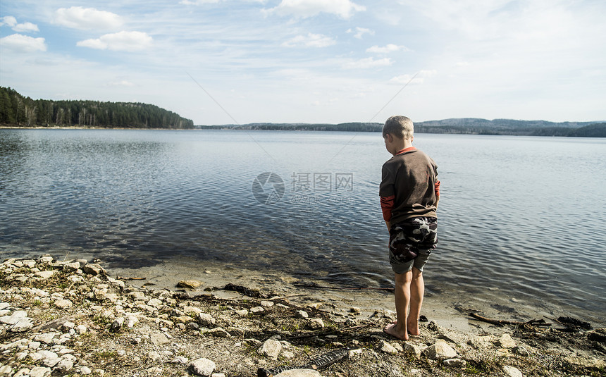 男孩站在湖边的后视图图片