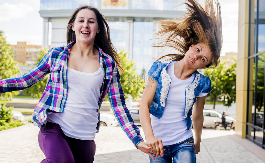 两名青年妇女一边摇头一边在城市奔跑图片