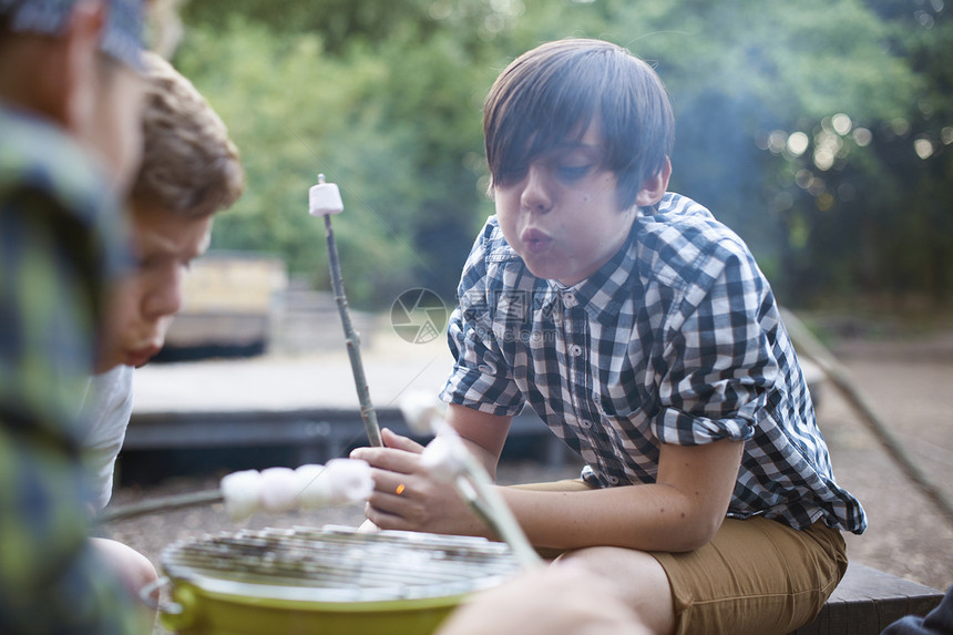 一群男孩在烤桶上烤棉花糖图片