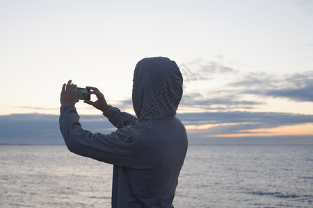 中年男子用智能手机拍摄大海图片