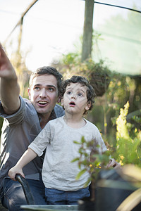 花园里年轻的父亲和惊讶的小孩儿子高清图片素材