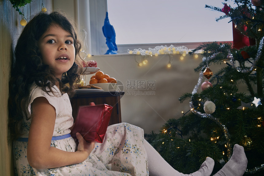 坐在地板上守着圣诞礼物的女童肖像图片
