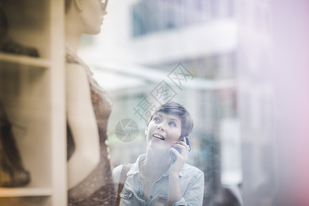 在户外看商店橱窗里衣服的成年女性图片